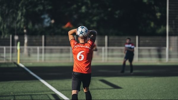 sports player throwing soccer ball