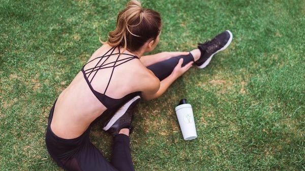 woman in athleisure stretching on grass