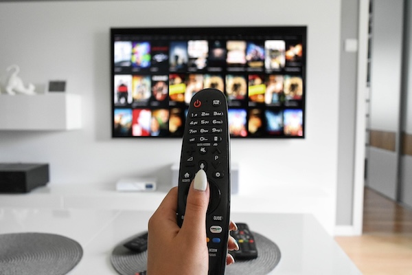 person holding tv remote watching sports docuseries